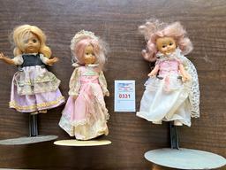 Three porcelain dolls with stands
